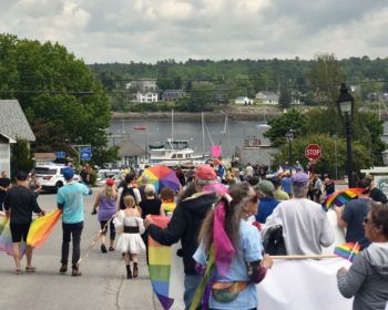 Pride Parade marchers in rainbow regalia marching down High Street overlooking the Belfast waterfront