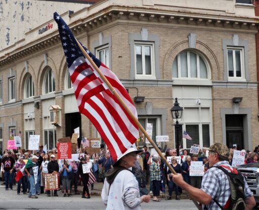 Protesters in Belfast, Maine, carrying signs and American flags.