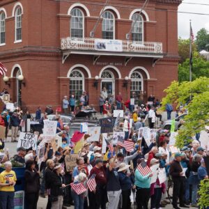 View of Belfast Post Office Square with protesters filling the parking lot with signs and US flags.