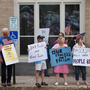 Protesters on the sidewalk in Belfast with signs reading "Voter Suppression is on the ballot in Maine," "BAD people need good trouble," Due process is not fascism," and "Fascism falls when the people rise."