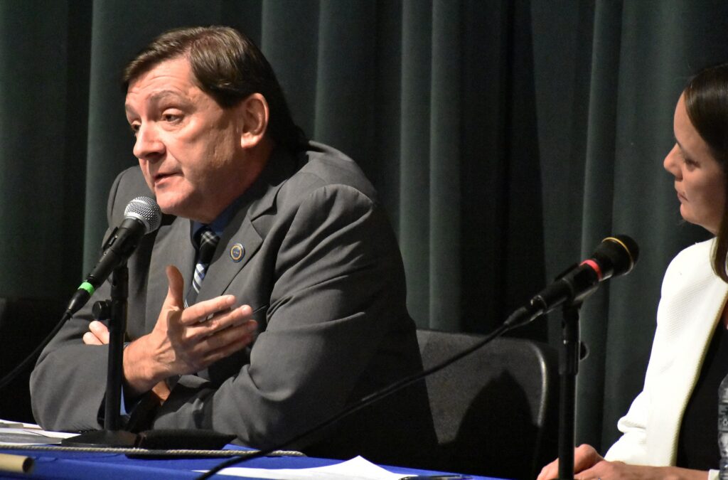 Candidate Troy Jackson, in a gray suit, speaks at the forum with Shenna Bellows looking on.