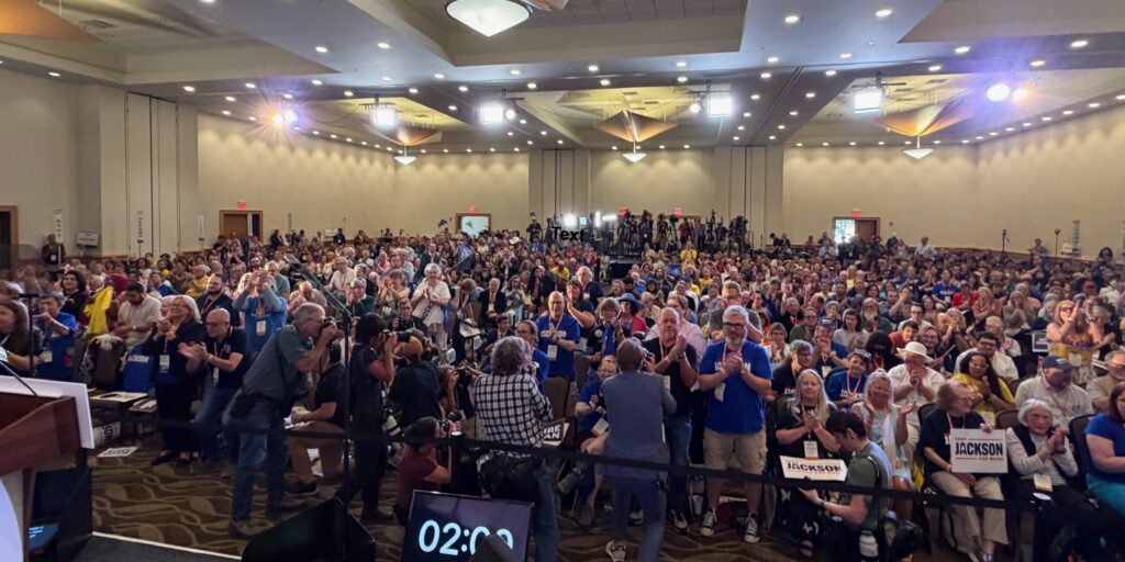 View of Senate Nominating Convention floor from the stage, showing nearly 600 delegates plus press in the foreground and background.