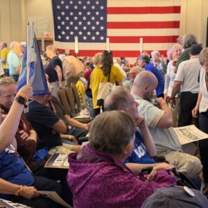 Delegates mingle on the convention floor in front of a huge American flag.